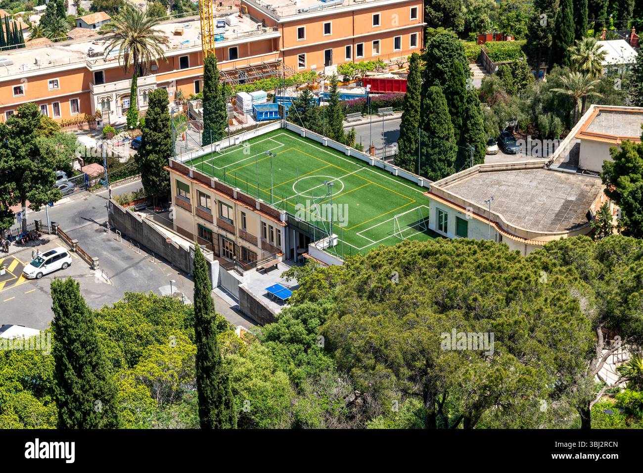 Taormina, Sizilien - Italie - 05-04-2025 : vue surélevée d'un terrain de football sur le toit entouré d'arbres et de bâtiments à Taormina avec art vert vif Banque D'Images