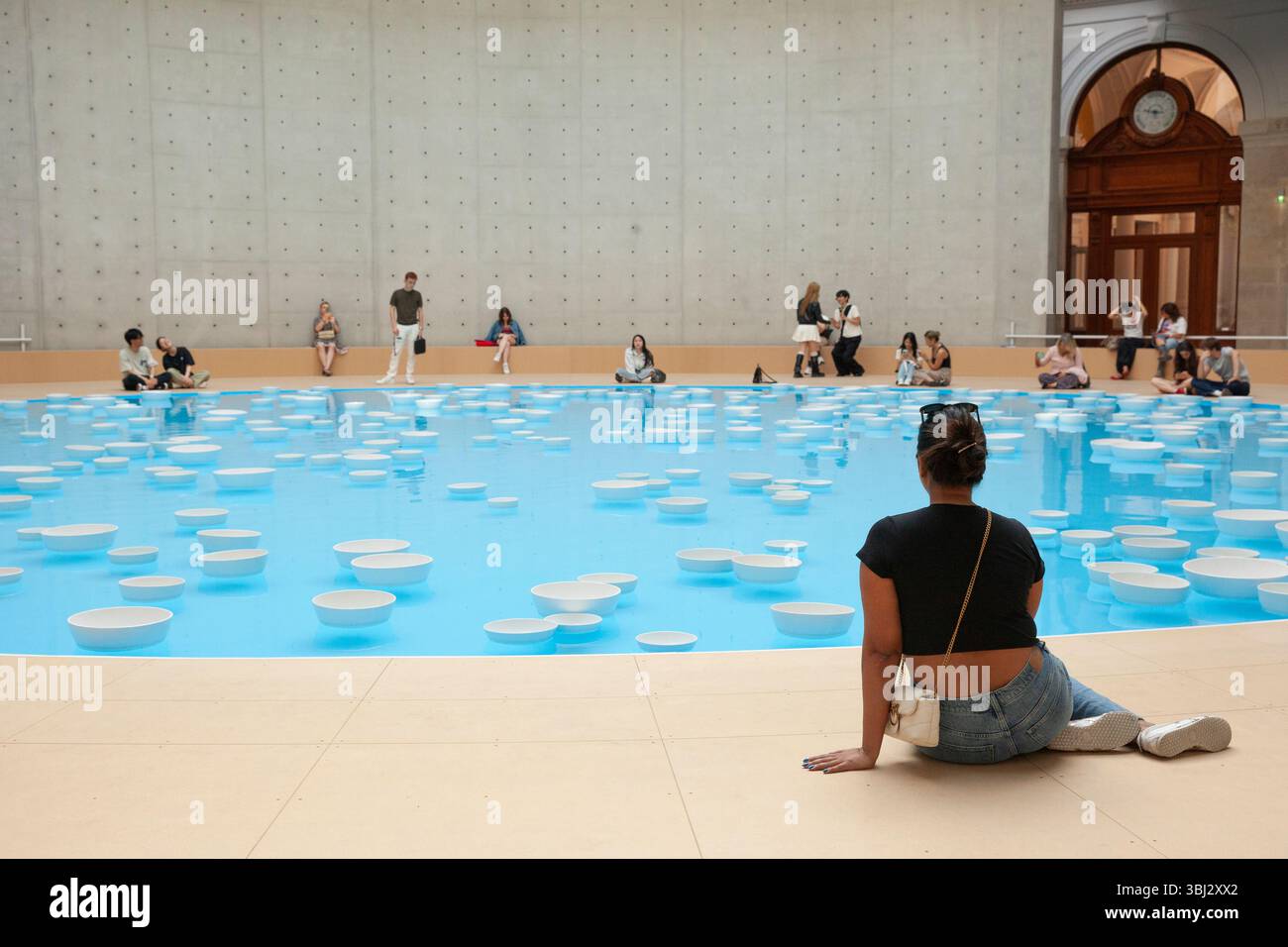 Paris, France. 12 juin 2025. Cet été, les visiteurs de la collection François Pinault de l'ancienne Bourse de commerce peuvent voir l'installation artistique 'clinamen' de l'artiste Celeste boursier-Mougenot. Il utilise des objets domestiques tels que ces bols en porcelaine, mais comme ils flottent autour de la piscine de 18m sous la rotonde, ils sonnent les uns contre les autres créant une expérience mélodieuse et reposante pour les yeux et les oreilles. Les visiteurs ont jusqu'au 21 septembre pour attraper l'installation. Crédit : Anna Watson/Alamy Live News Banque D'Images