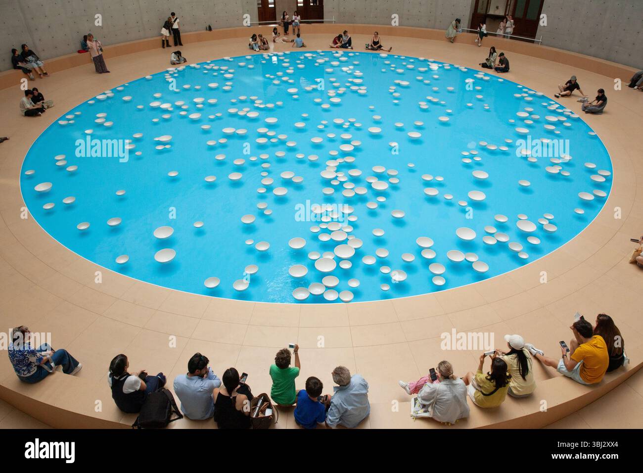 Paris, France. 12 juin 2025. Cet été, les visiteurs de la collection François Pinault de l'ancienne Bourse de commerce peuvent voir l'installation artistique 'clinamen' de l'artiste Celeste boursier-Mougenot. Il utilise des objets domestiques tels que ces bols en porcelaine, mais comme ils flottent autour de la piscine de 18m sous la rotonde, ils sonnent les uns contre les autres créant une expérience mélodieuse et reposante pour les yeux et les oreilles. Les visiteurs ont jusqu'au 21 septembre pour attraper l'installation. Crédit : Anna Watson/Alamy Live News Banque D'Images