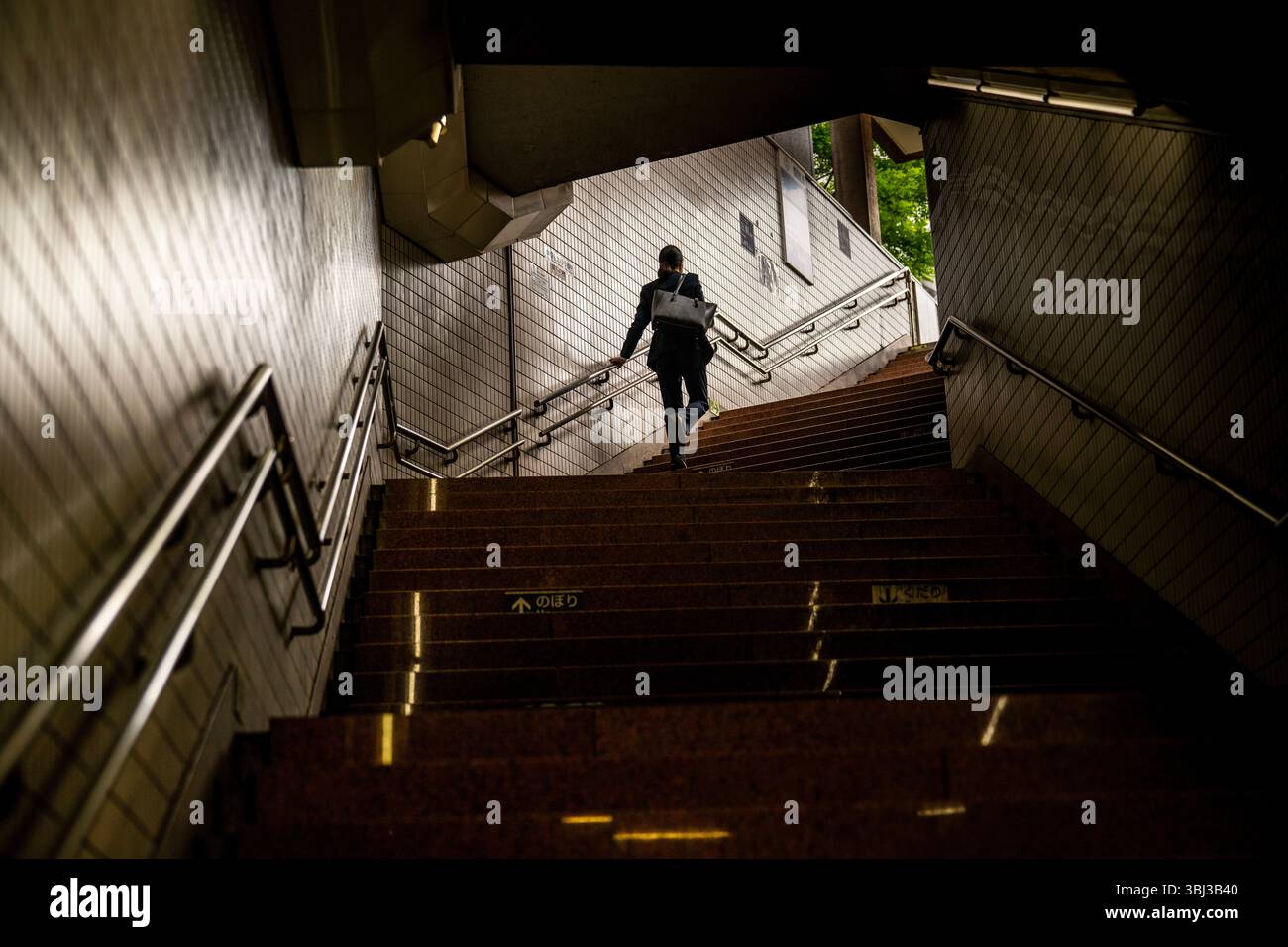 Une femme d'affaires grimpant les escaliers du métro dans une lumière spectaculaire à Tokyo, au Japon Banque D'Images