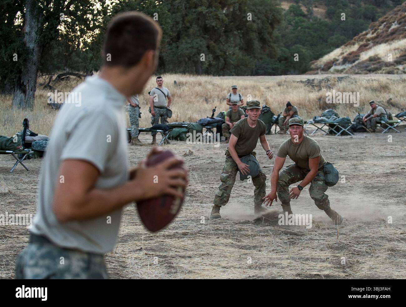 Les soldats de l'armée américaine jouent au football ensemble sur un terrain ouvert en Californie après une journée complète d'entraînement, profitant du temps d'arrêt pendant les exercices militaires. Banque D'Images Les soldats de l'armée américaine jouent au football ensemble sur un terrain ouvert en Californie après une journée complète d'entraînement, profitant du temps d'arrêt pendant les exercices militaires. Banque D'Images