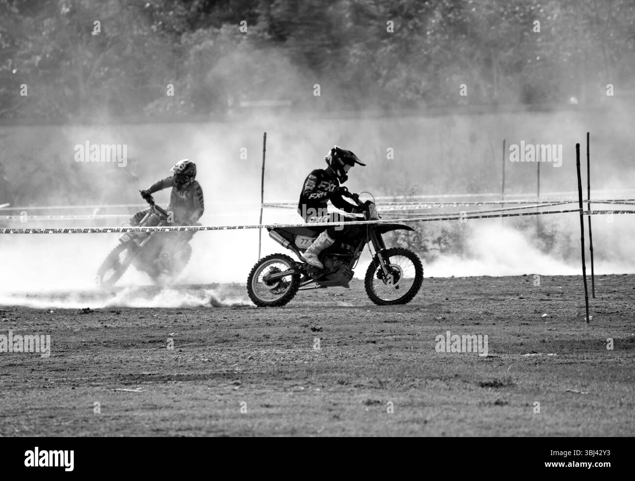 Les motards tout-terrain courent sur une piste poussiéreuse lors d'un rallye moto en Inde, mettant en valeur leurs compétences, leur vitesse et leur adernaline. Banque D'Images