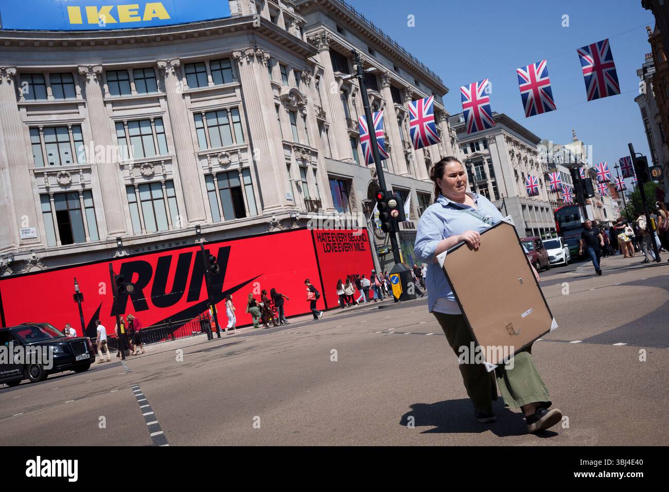 Un acheteur porte un cadre IKEA et traverse Oxford Circus où la nouvelle boutique IKEA a récemment ouvert à Westminster, le 12 juin 2025, à Londres, en Angleterre. Banque D'Images