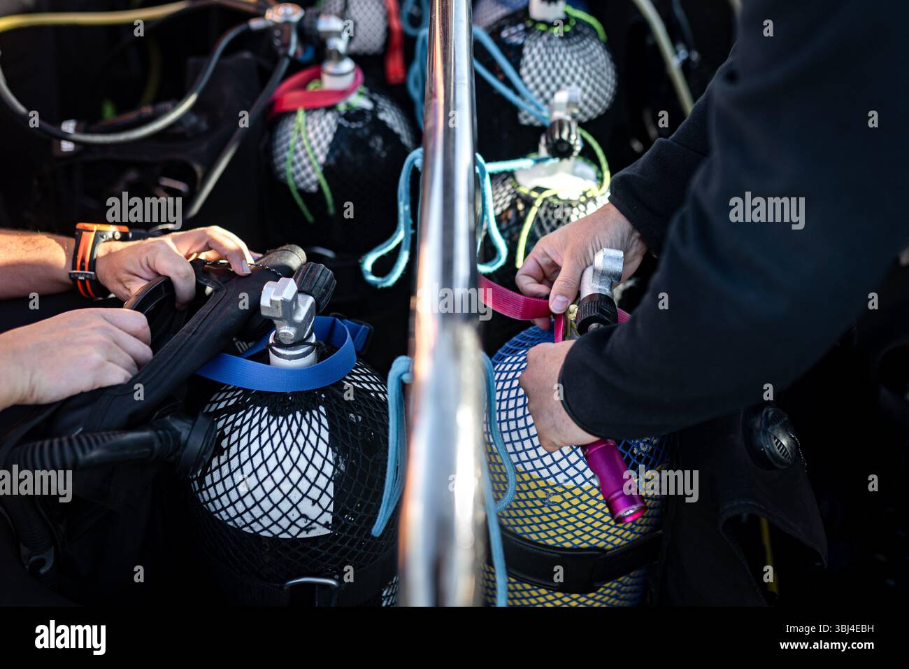 Plongeurs préparant l'équipement sur un bateau de plongée, connectant les régulateurs aux réservoirs d'oxygène pour une exploration sous-marine en toute sécurité Banque D'Images