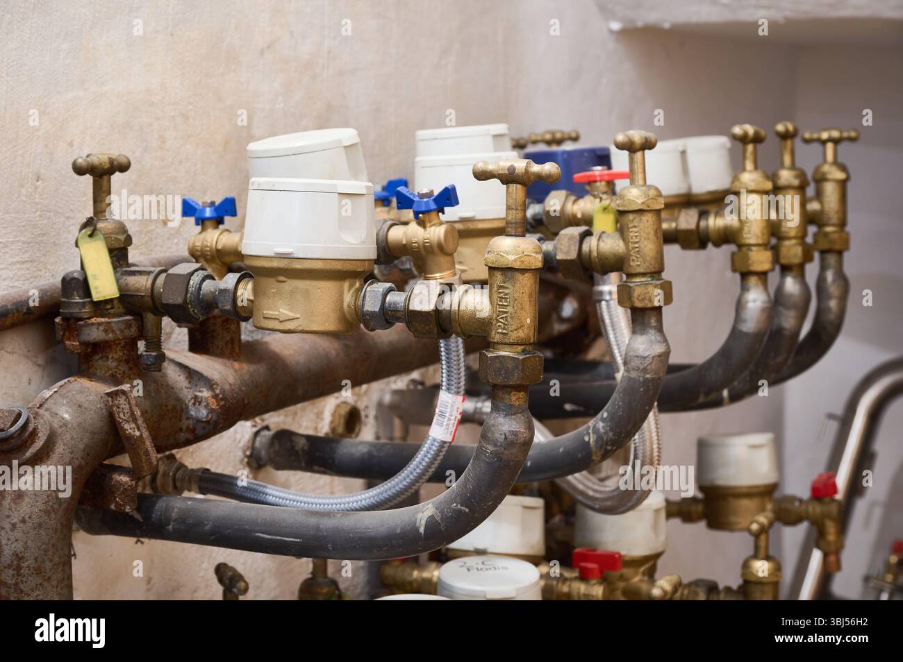 Gros plan des compteurs d'eau et des vannes régulant le débit d'eau dans un bâtiment résidentiel, assurant une mesure précise de la consommation individuelle Banque D'Images