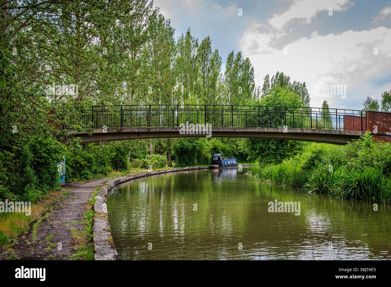 Un petit pont surplombe le Grand Union canal à Milton Keynes, entouré d'une végétation luxuriante Banque D'Images