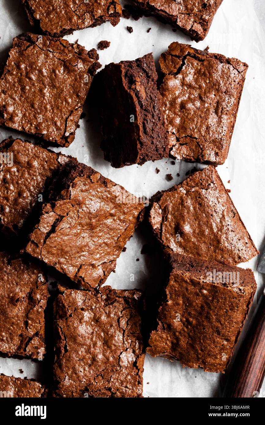 Une vue de dessus de brownies au chocolat avec un dessus croustillant sur papier parchemin. Banque D'Images