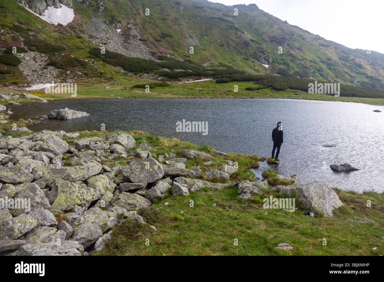 Randonnées en plein air à travers le lac couvert de pierre dans une nature sauvage isolée. Paysage de montagne spectaculaire avec ciel nuageux et eau immaculée. Banque D'Images