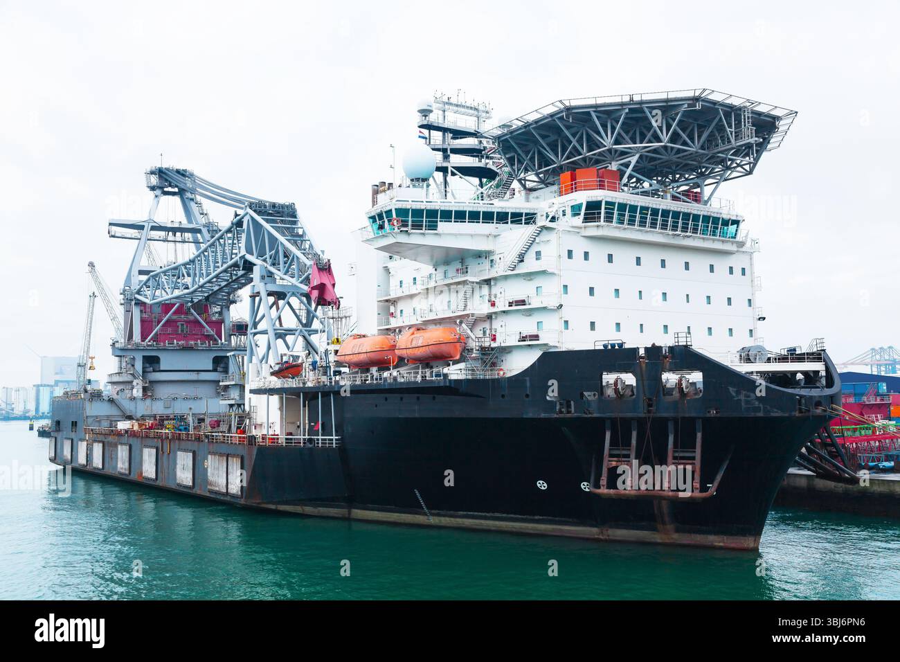 Un grand navire grue flottante offshore avec une grue et un héliport est amarré dans le port maritime de Rotterdam. Banque D'Images