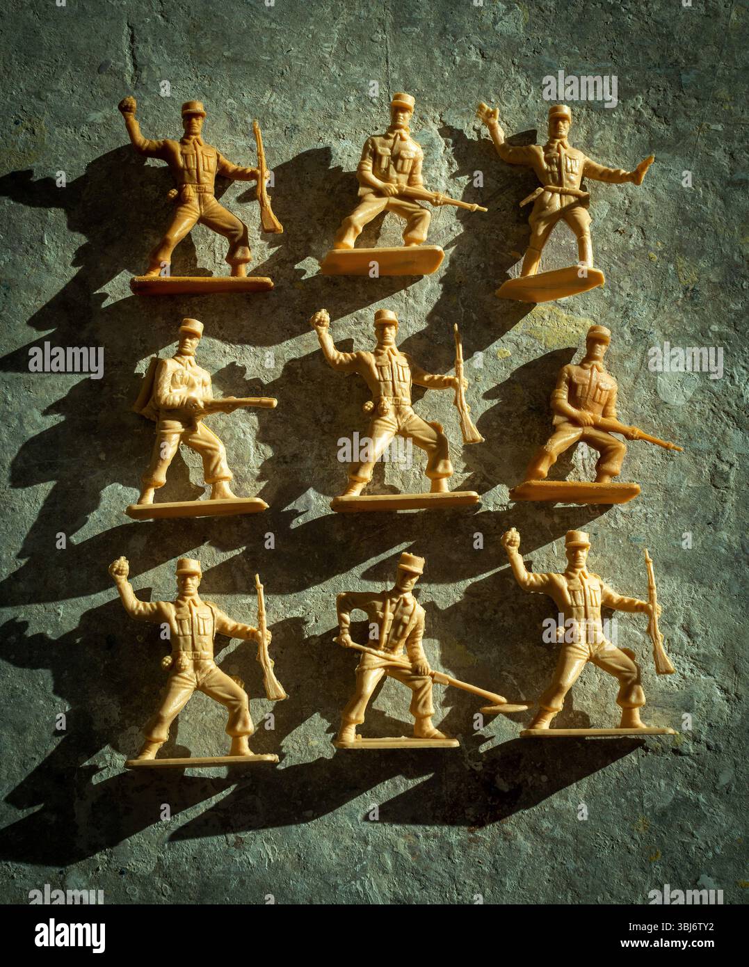 Les soldats jouets en plastique sont exposés dans différentes poses d'action sur une surface texturée, projetant des ombres qui mettent en valeur leurs formes. Banque D'Images
