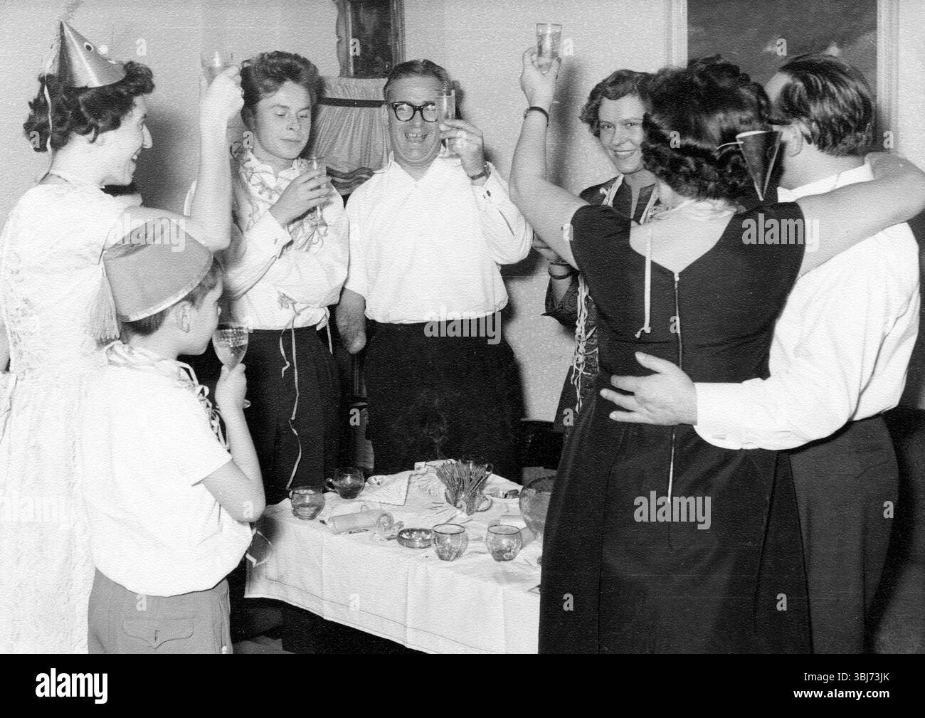 Toast au champagne de la Saint-Sylvestre, 1940, adultes célébrant ensemble avec des verres levés dans une atmosphère joyeuse, photo historique Banque D'Images