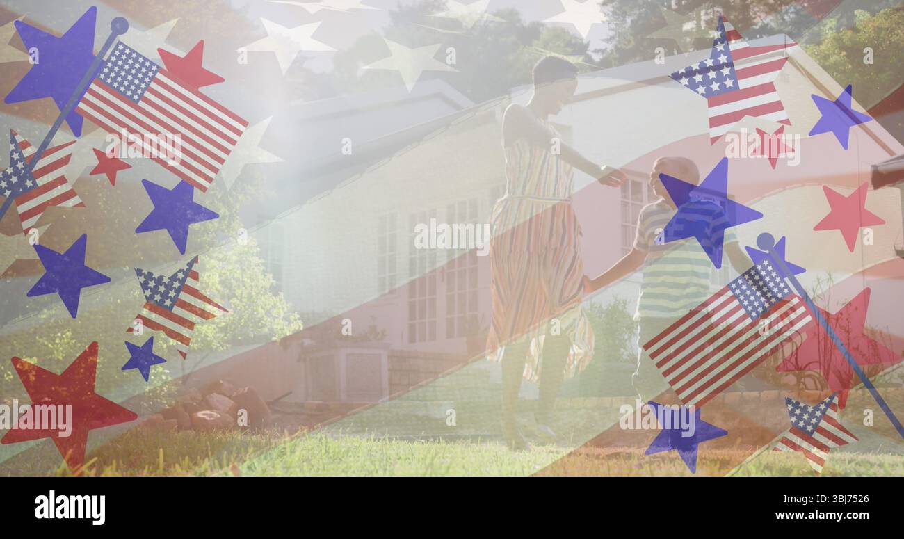 Mère dansante portant une robe rayée et fils dansant sur la cour avant herbeuse, avec des étoiles et des drapeaux Banque D'Images