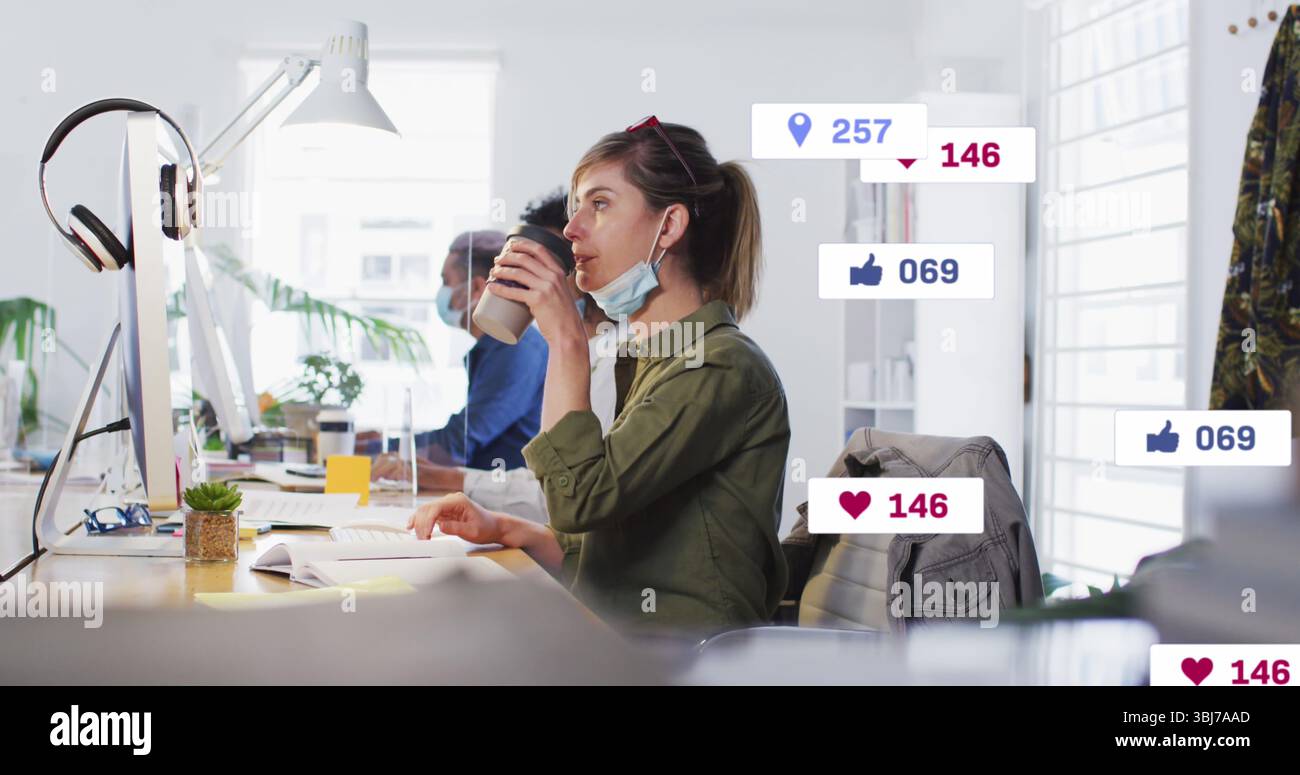 Femme buvant en chemise verte sirotant du café tout en regardant le moniteur au bureau ouvert, avec succulent Banque D'Images