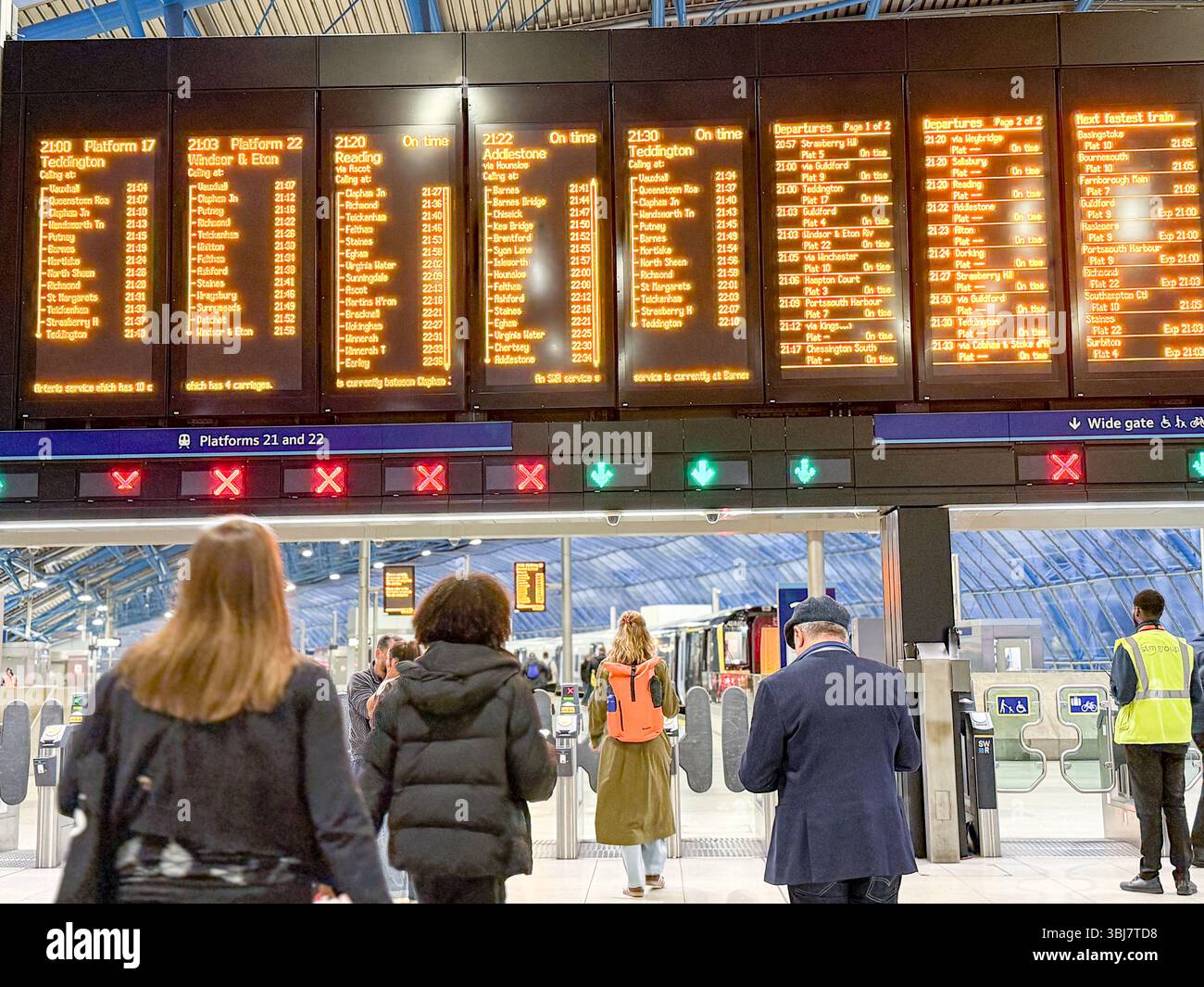 Les navetteurs vérifient les informations sur le train sur l'écran LED numérique au-dessus des barrières de billets à la gare de Waterloo—dernier coup d'œil avant le début de la ruée d'embarquement. Banque D'Images