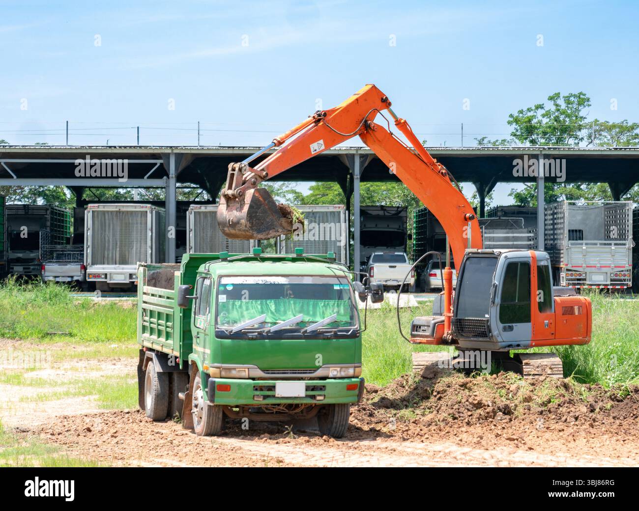 La pelle excavatrice ramasse le sol et le charge dans le tombereau à benne basculante dans les locaux de l'usine. Banque D'Images