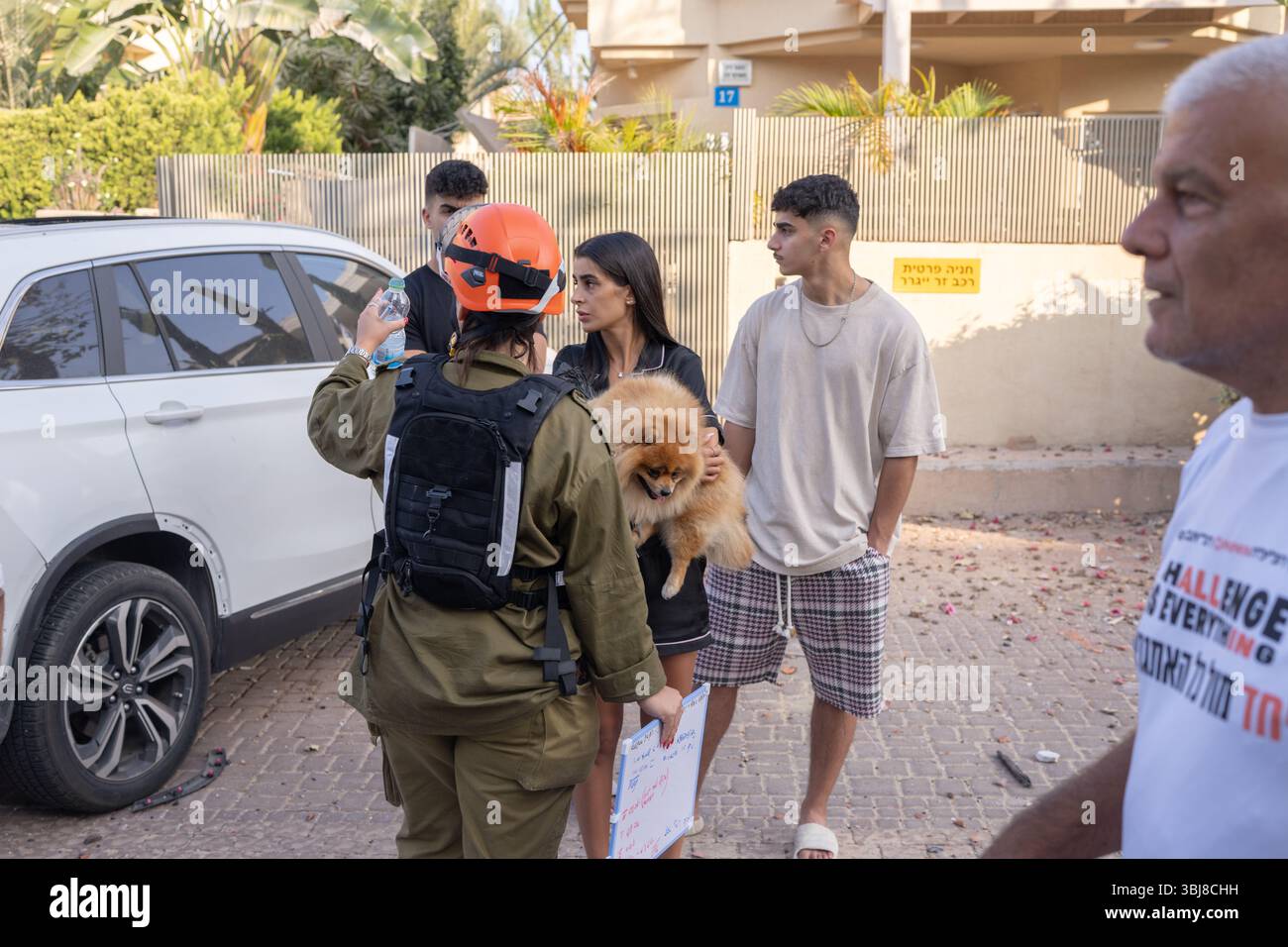 Rishon LeZion, Israël. 14 juin 2025. Un travailleur d’urgence parle à People Walk a après qu’un missile iranien ait frappé Rishon LeZion, tuant au moins deux personnes et en blessant plusieurs autres. Crédit : Ilia Yefimovich/dpa/Alamy Live News Banque D'Images