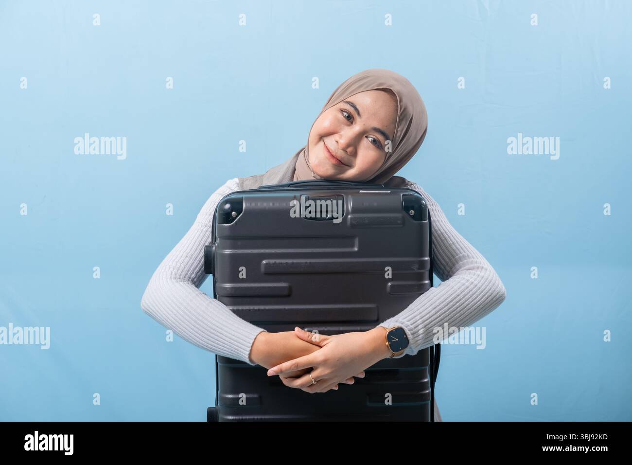 Une femme tient une valise noire et sourit. Concept d'aventure et d'excitation, comme la femme se prépare pour un voyage. Banque D'Images