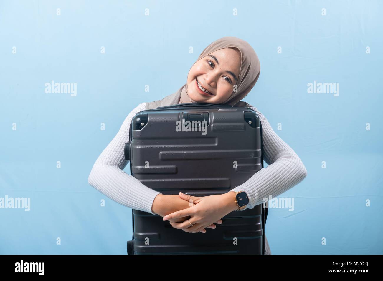 Une femme tient une valise noire et sourit. Concept d'aventure et d'excitation, comme la femme se prépare pour un voyage. Banque D'Images