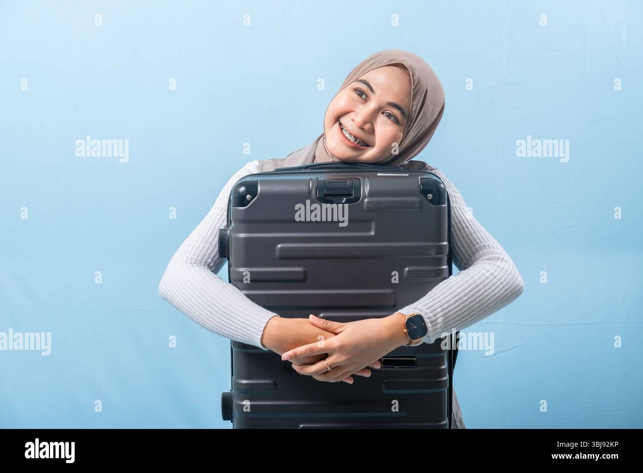 Une femme tient une valise noire et sourit. Concept d'aventure et d'excitation, comme la femme se prépare pour un voyage. Banque D'Images