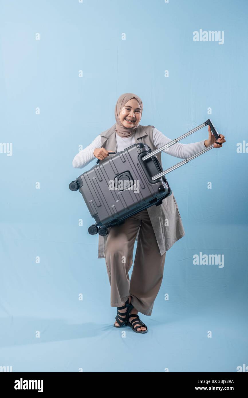 Une femme tient une valise et sourit. Concept d'aventure et d'excitation, comme la femme se prépare pour un voyage Banque D'Images