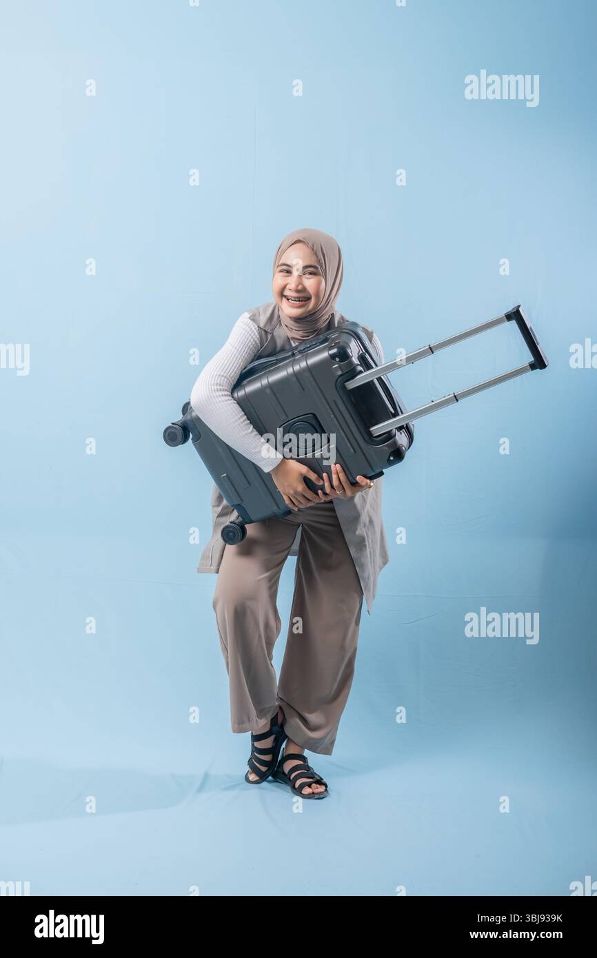 Une femme tient une valise et sourit. Concept d'aventure et d'excitation, comme la femme se prépare pour un voyage Banque D'Images