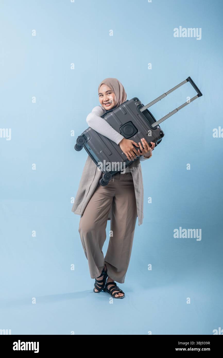 Une femme tient une valise et sourit. Concept d'aventure et d'excitation, comme la femme se prépare pour un voyage Banque D'Images