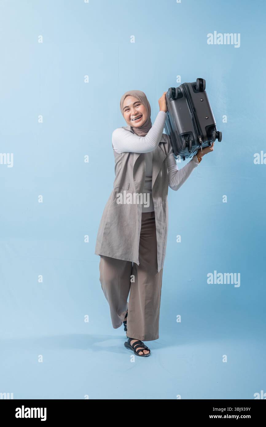 Une femme tient une valise et sourit. Concept d'aventure et d'excitation, comme la femme se prépare pour un voyage Banque D'Images