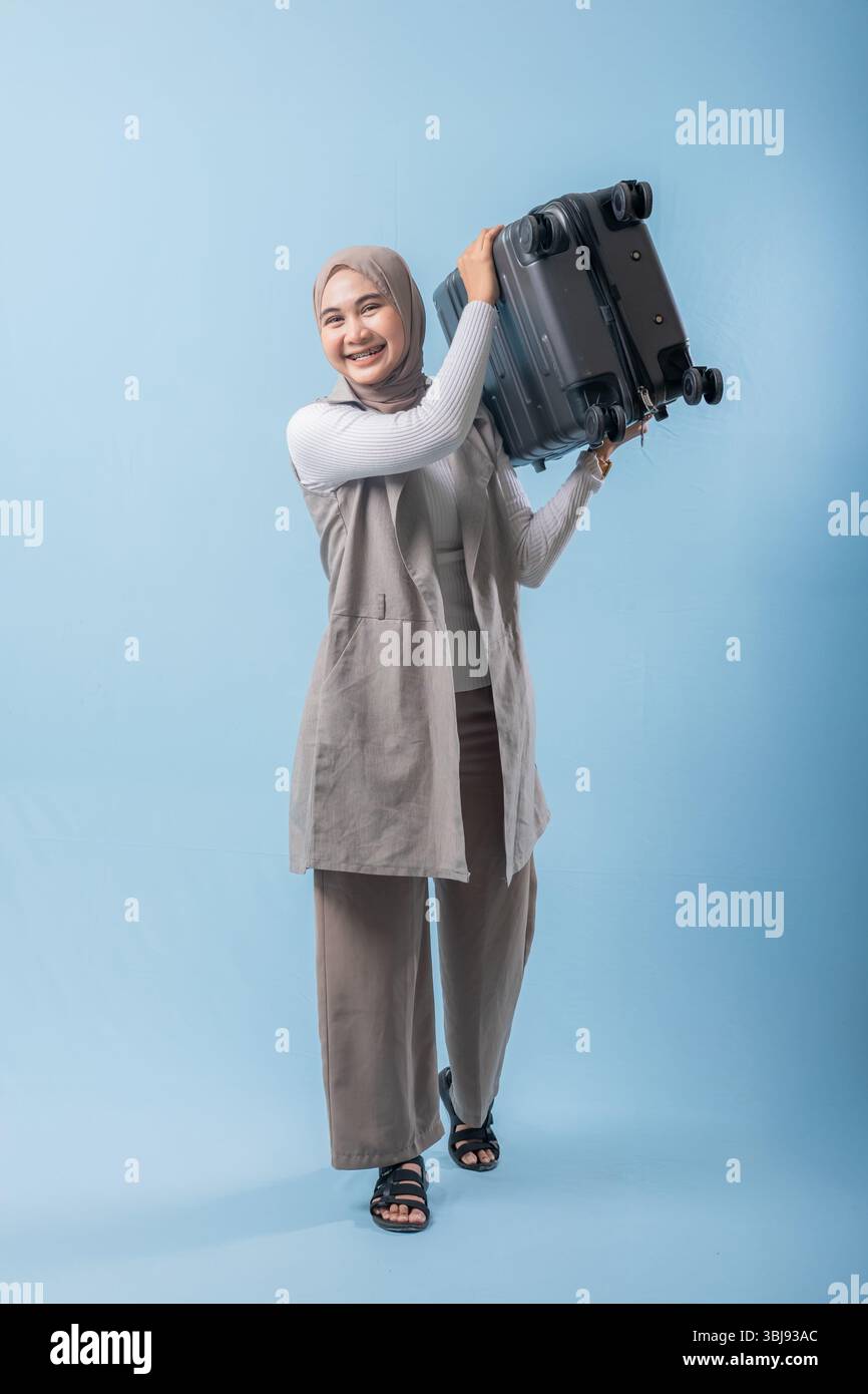 Une femme tient une valise et sourit. Concept d'aventure et d'excitation, comme la femme se prépare pour un voyage Banque D'Images