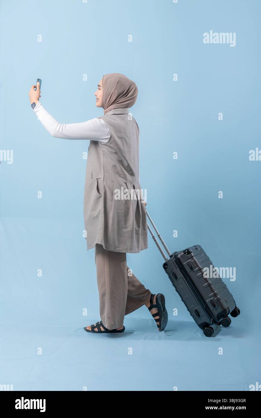 Une femme marche avec une valise et se prend en photo. Concept de voyage et d'aventure, alors que la femme se prépare à se lancer dans un voyage Banque D'Images