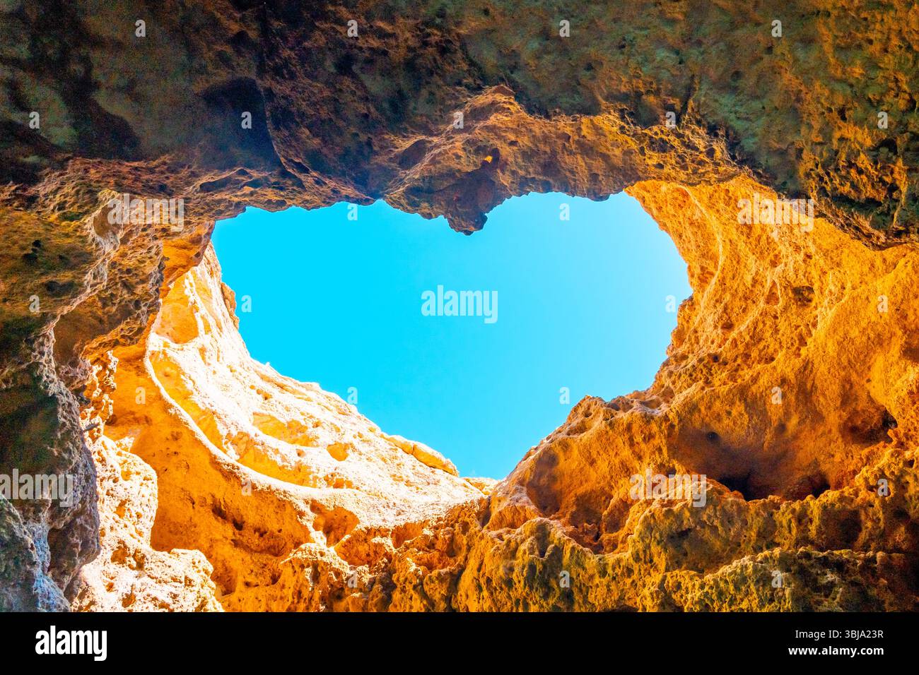 Ouverture naturelle en forme de coeur dans une grotte Benagil le long de la côte de l'Algarve au Portugal. Banque D'Images