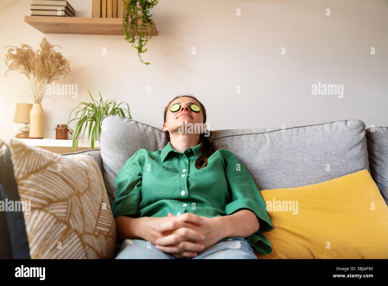 Femme détendue appréciant la routine de beauté avec des tranches de concombre sur les yeux à la maison Banque D'Images