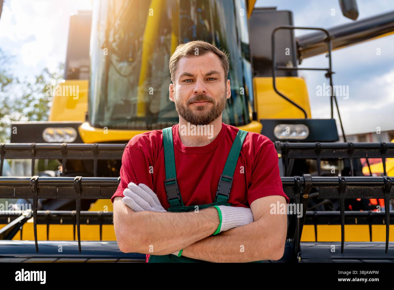 Opérateur de moissonneuse-batteuse homme confiant debout devant la moissonneuse-batteuse. Banque D'Images
