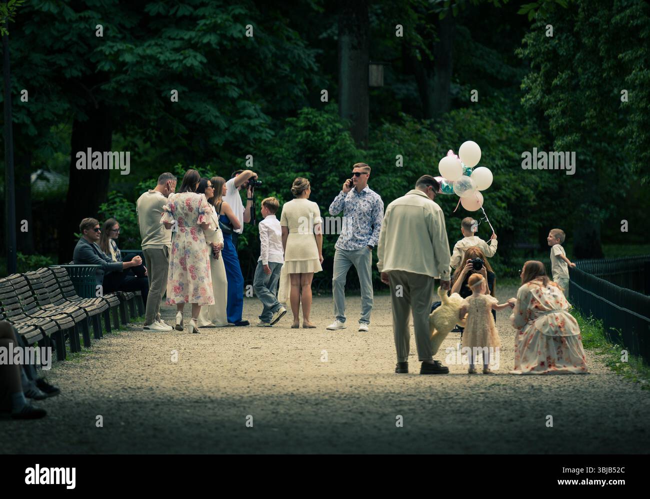 Les gens habillés élégamment rassemblant et prenant des photos lors d'une fête dans un parc public pendant l'été avec des ballons blancs Banque D'Images