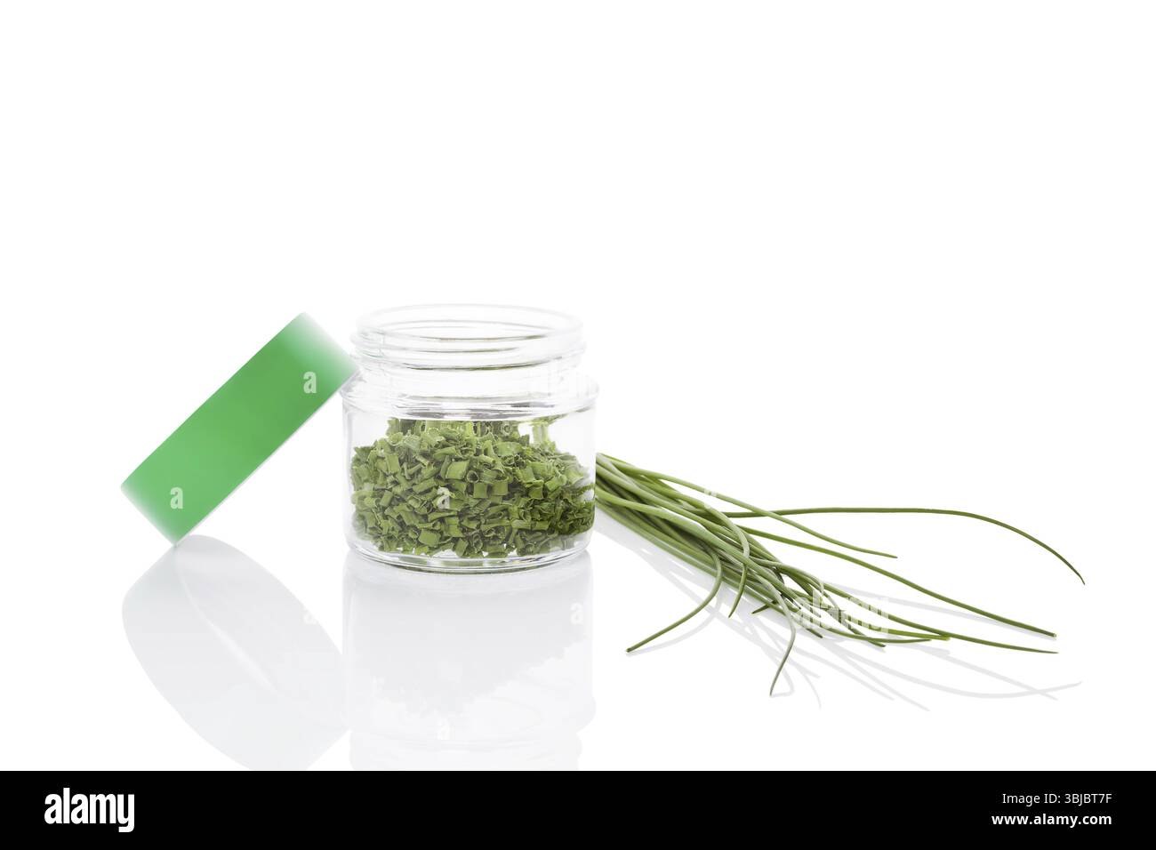 Ciboulette fraîche et épice de ciboulette sèche dans un pot en verre isolé sur fond blanc. Herbes aromatiques culinaires saines. Fines herbes, arts culinaires Banque D'Images