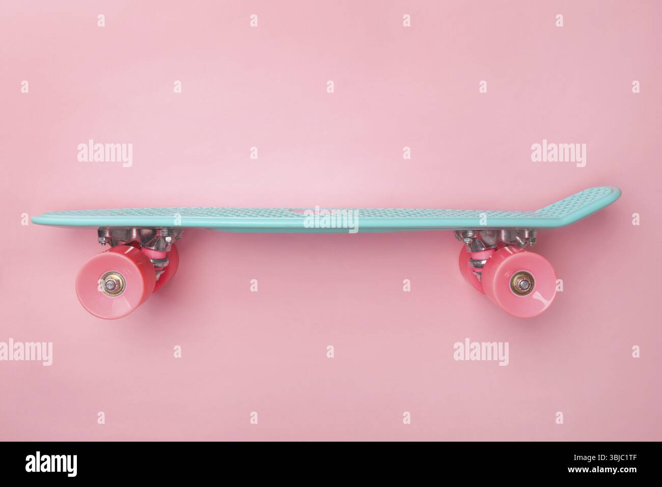 Vue latérale de planche à roulettes de Penny sur fond rose. Mini croiseur Banque D'Images