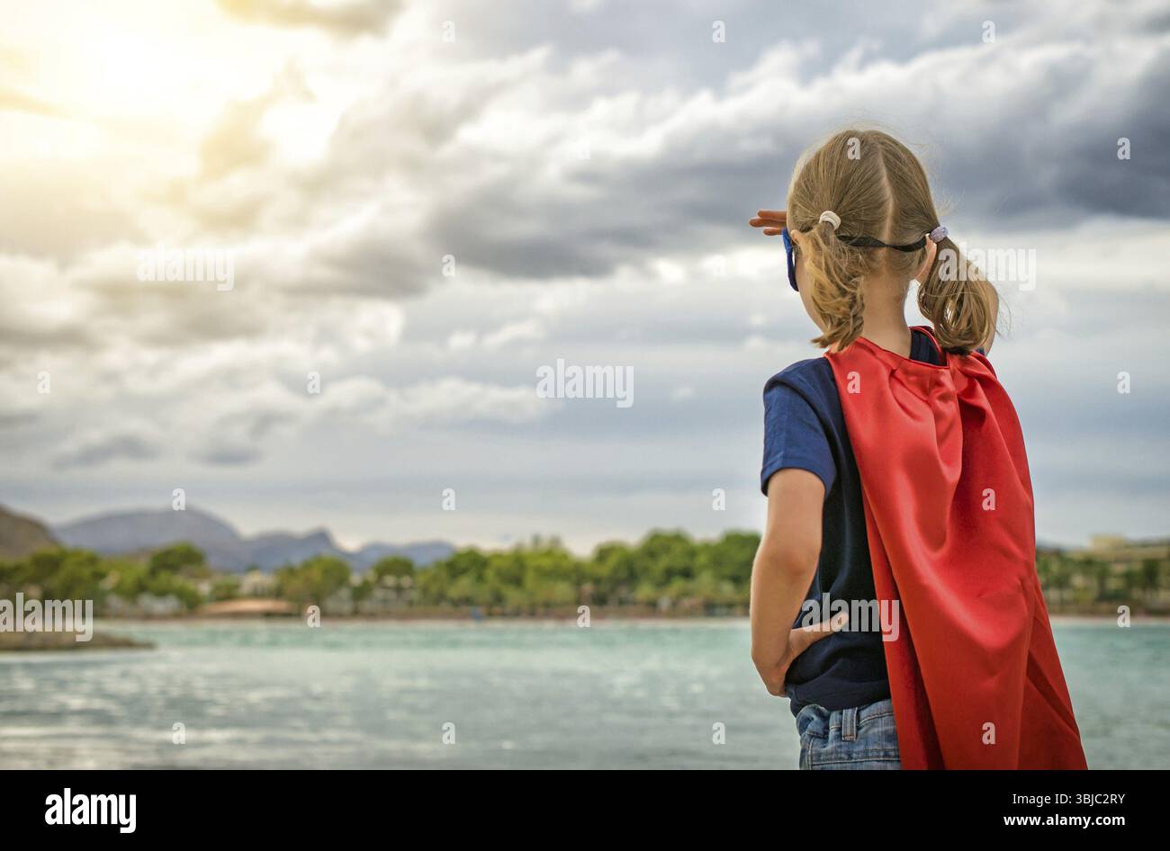 Super-héros enfant regardant sur le coucher du soleil Banque D'Images