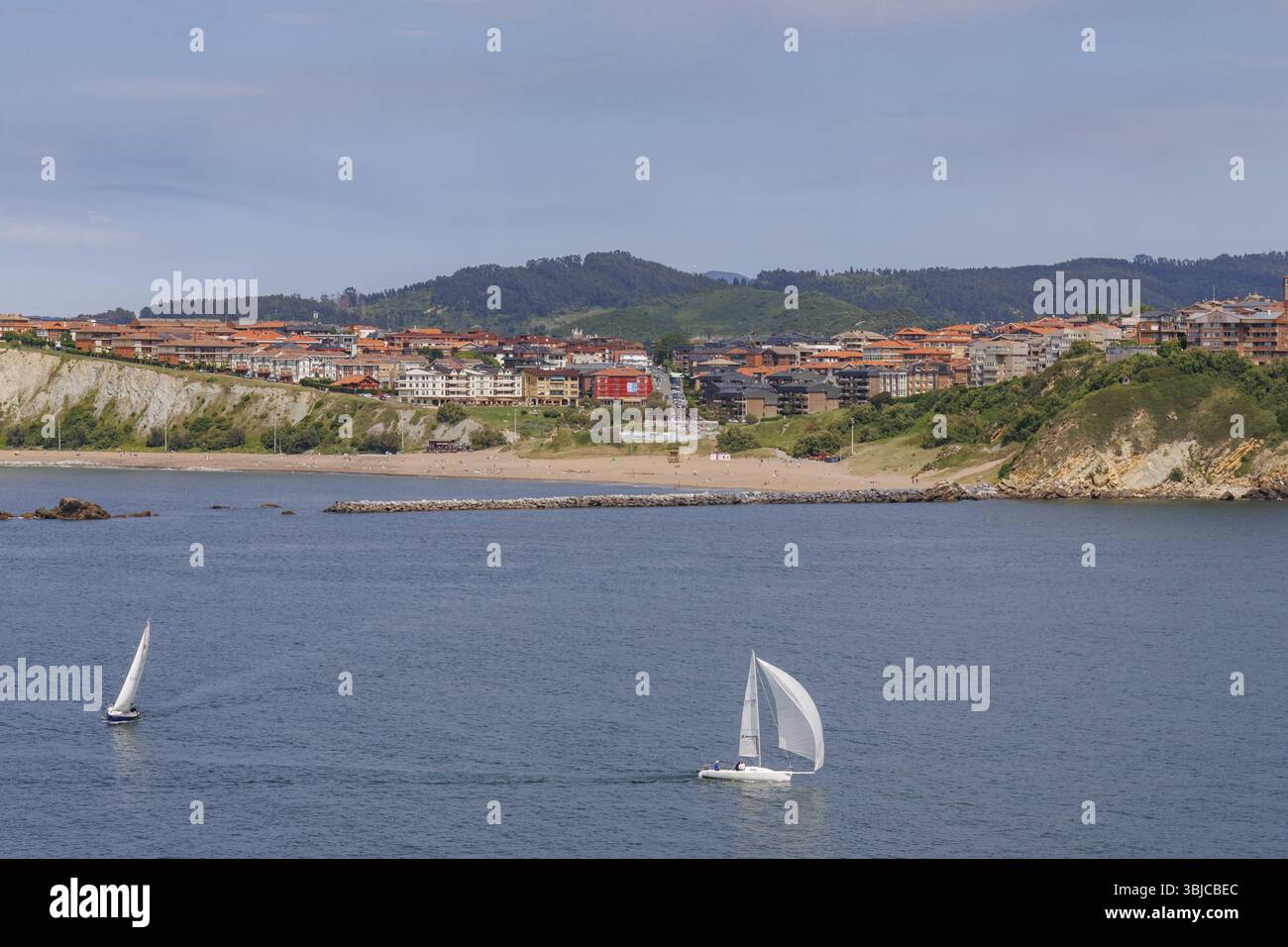 Deux voiliers sur la mer calme devant la ville côtière et ciel nuageux, Gexto, pays Basque, Espagne, Europe Banque D'Images