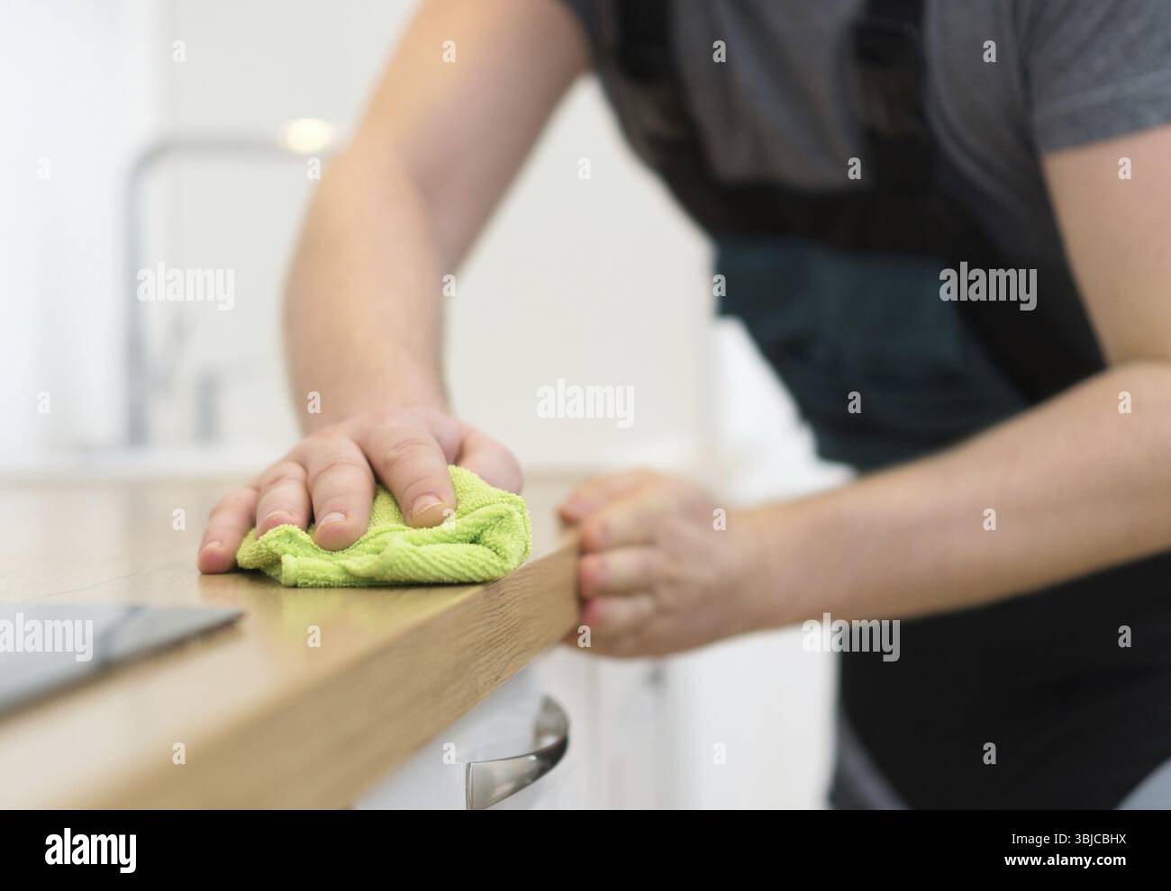 Concept de service de nettoyage. Homme nettoyant des meubles de cuisine Banque D'Images