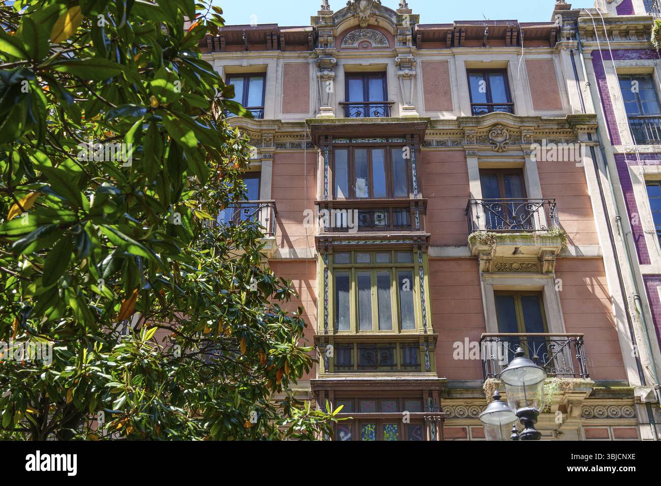 Façade historique avec balcons, plantes et éléments de design classiques, entourée d'arbres verts, Gijon, Asturies, Espagne, Europe Banque D'Images