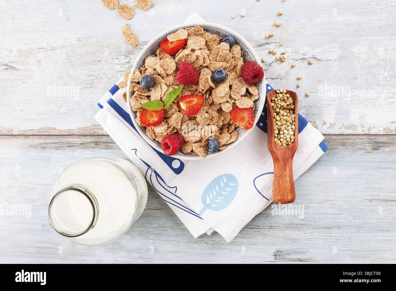 Bol de petit déjeuner avec des flocons d'avoine et des baies saines avec du lait d'en haut sur une table en bois Banque D'Images