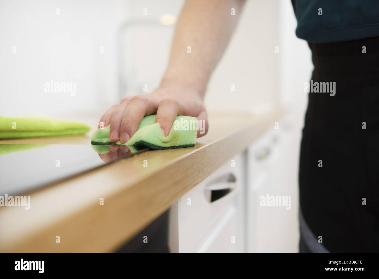 Concept de service de nettoyage. Homme nettoyant des meubles de cuisine Banque D'Images