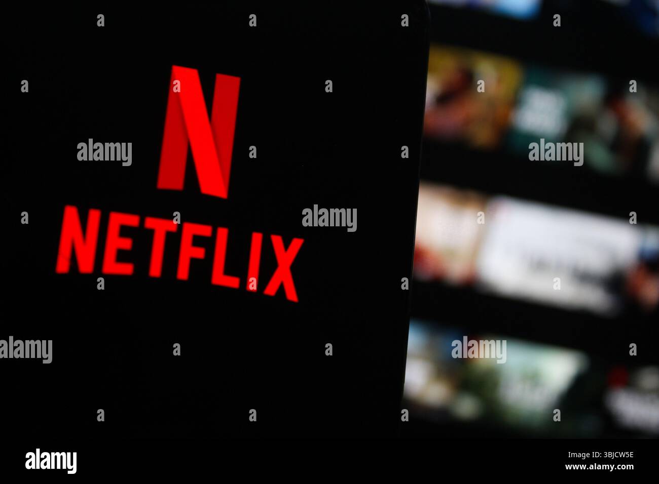 Logo Netflix sur un écran de téléphone avec l'écran d'accueil Netflix en arrière-plan. Indonésie - 15 mai 2025 Banque D'Images