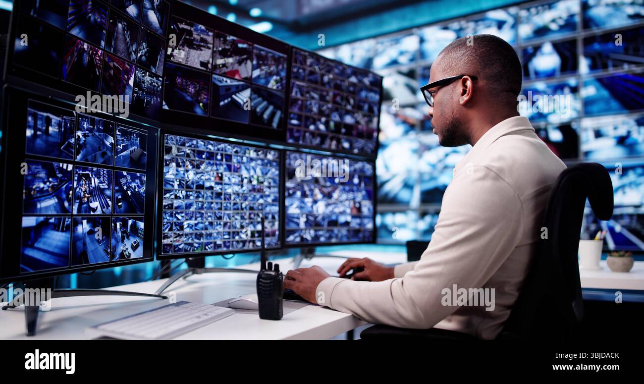 Le garde de sécurité afro-américain surveille les images de surveillance sur plusieurs écrans. Banque D'Images