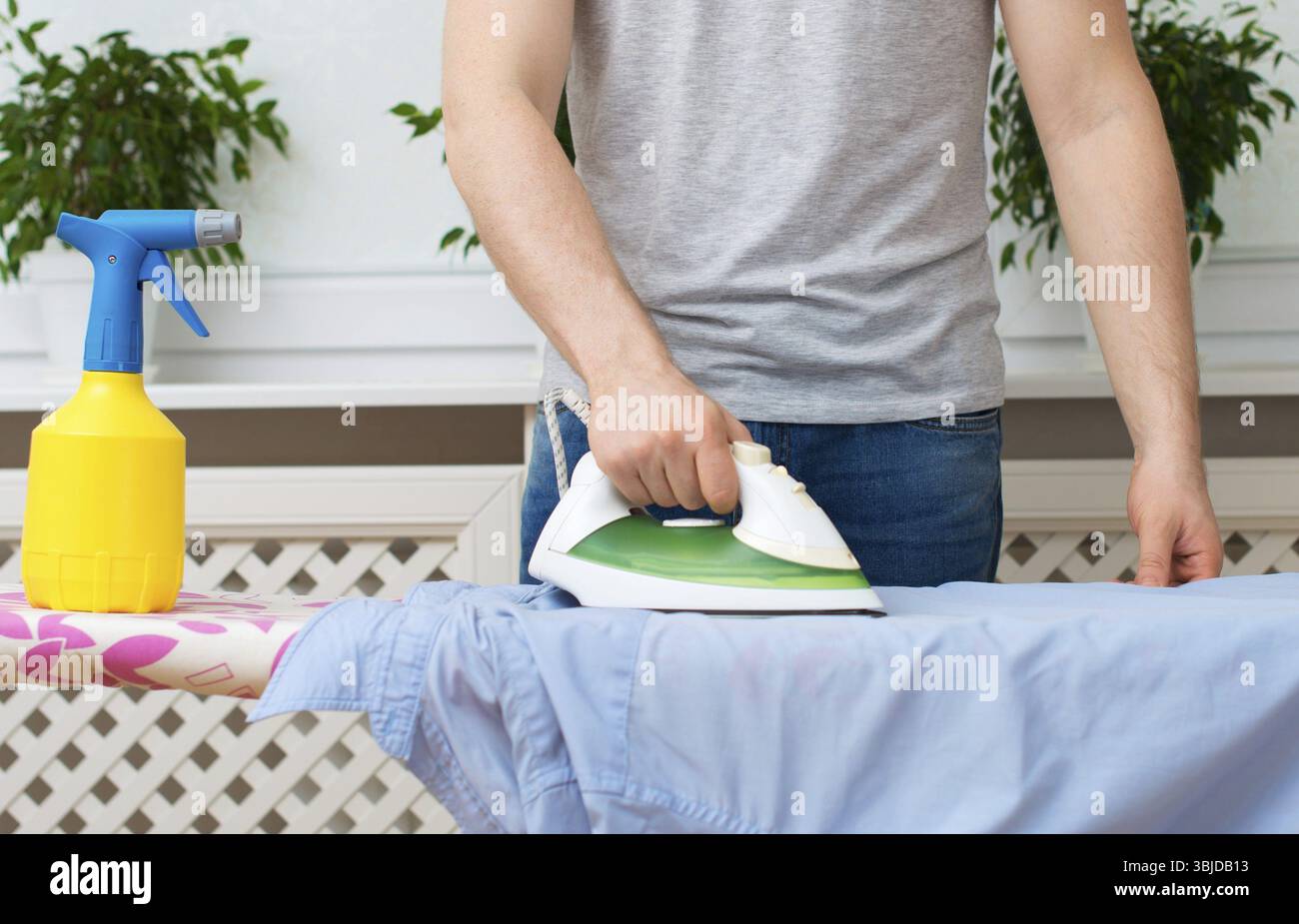 Homme repassant des vêtements sur une planche à repasser à la maison Banque D'Images