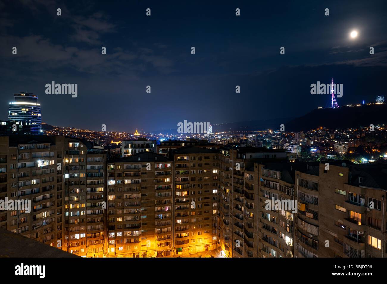 Paysage urbain de Tbilissi, Géorgie, la nuit avec des bâtiments, des lumières et une Lune brillante Banque D'Images