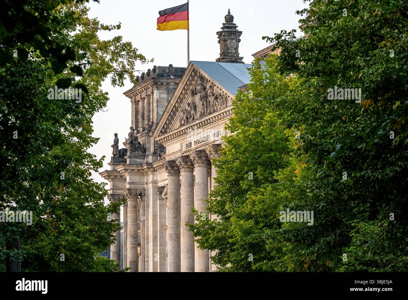 Le portail d'entrée du Reichstag à Berlin vu à travers quelques arbres Banque D'Images