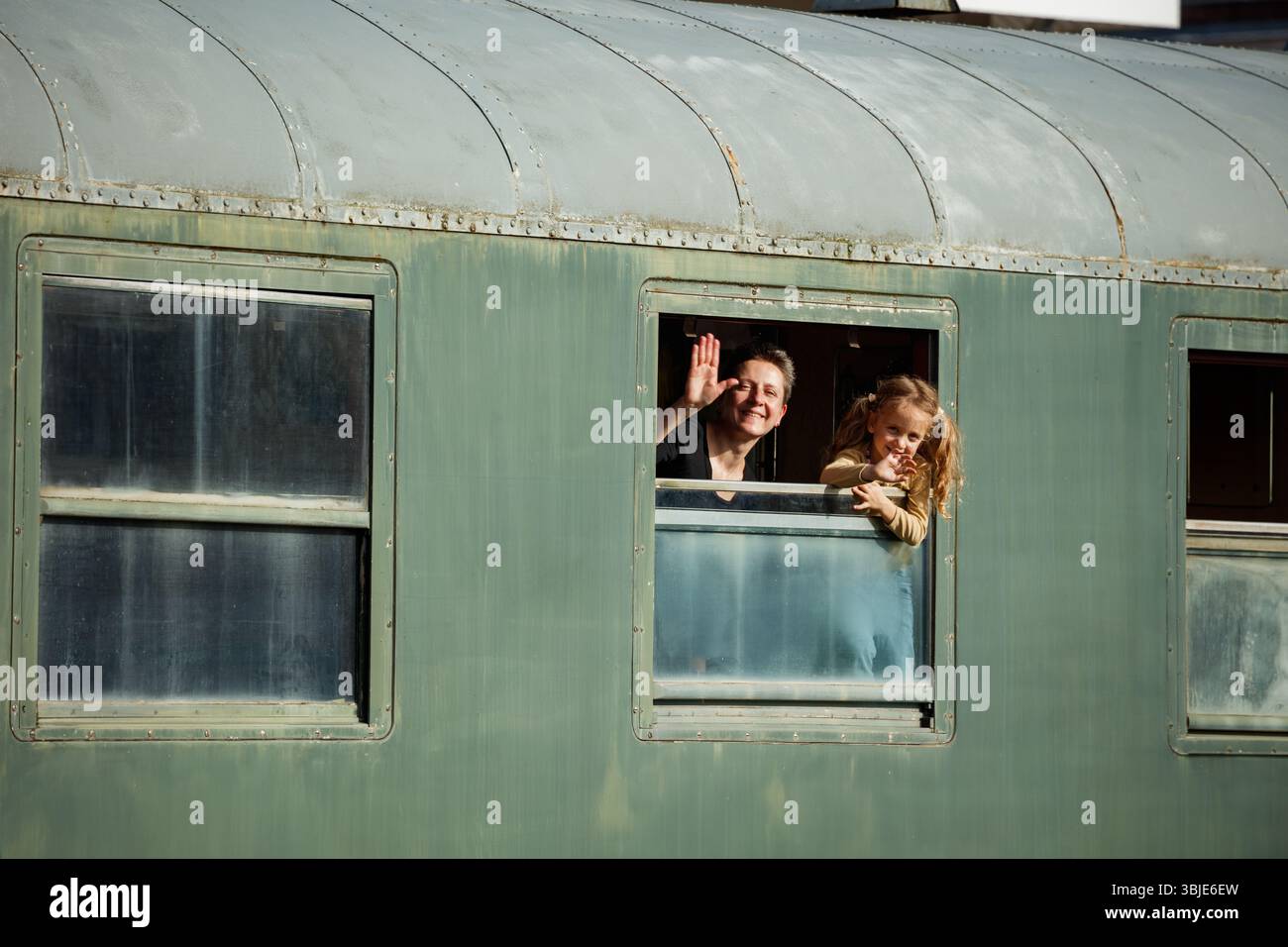 Mère avec l'enfant vague de la fenêtre du train dans la lumière chaude de l'après-midi Banque D'Images