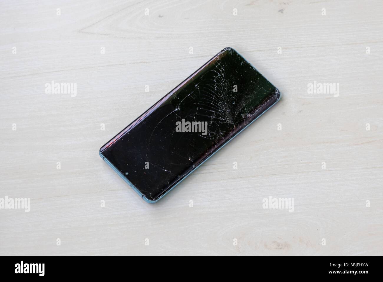 Smartphone avec écran fissuré sur fond en bois. Téléphone portable endommagé, écran cassé. Banque D'Images