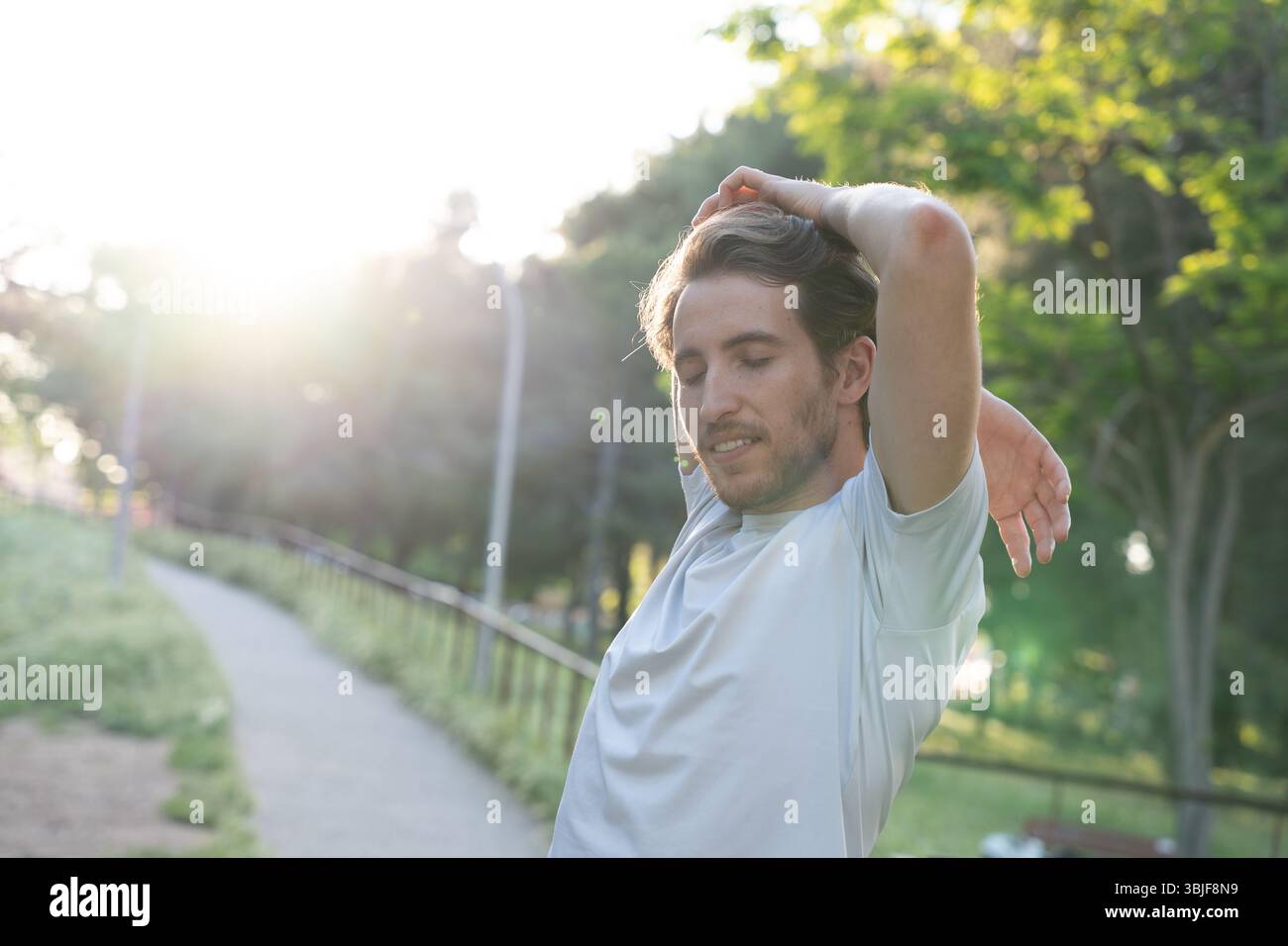 Homme étirant les muscles dans le parc au coucher du soleil Banque D'Images