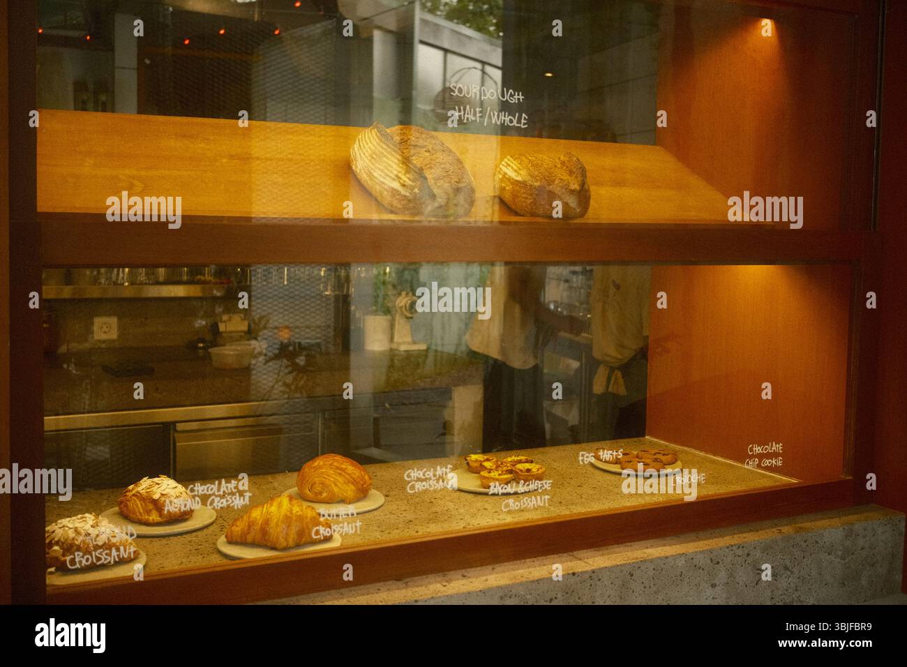 Vitrine de boulangerie comprenant des pains au levain, des croissants et des biscuits avec des étiquettes manuscrites Banque D'Images